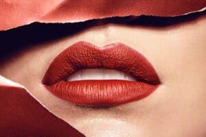 Close up of a woman's lips wearing red lipstick after a botox lip flip.